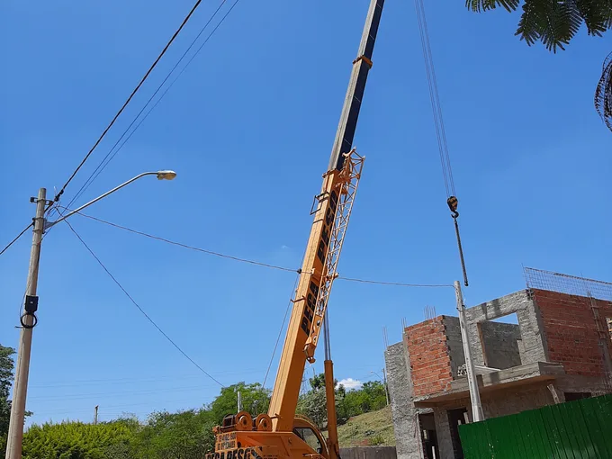 Guindaste Pega Peso içando material em obra residencial, próximo à rede elétrica, em Piracicaba