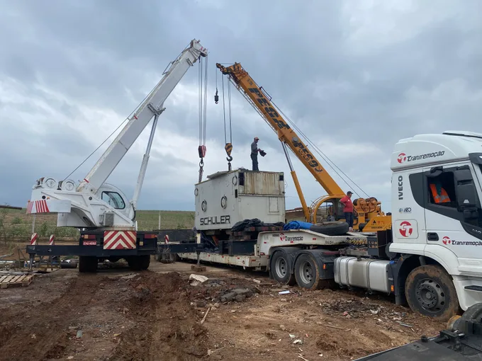 Dois guindastes Pega Peso descarregando uma máquina industrial Schuler de uma carreta em Piracicaba